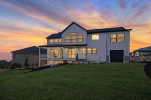 Back house at summer dusk with a garage and a lawn