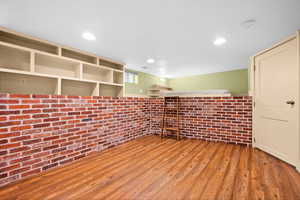 Empty room with light wood-type flooring and brick wall