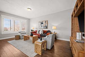 Living room featuring a textured ceiling and dark hardwood / wood-style floors