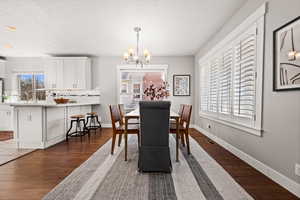 Dining space featuring a notable chandelier, a healthy amount of sunlight, and dark wood-type flooring