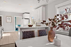 Kitchen featuring kitchen peninsula, white cabinetry, a healthy amount of sunlight, and white appliances