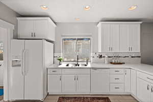 Kitchen featuring decorative backsplash, sink, white cabinets, and white appliances