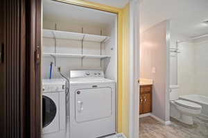 Washroom featuring washing machine and clothes dryer and light hardwood / wood-style flooring