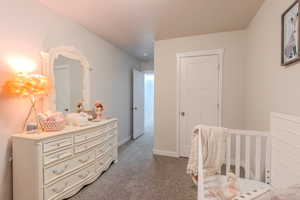 Carpeted bedroom view 2 featuring a nursery area