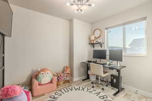 Home office with light wood-type flooring and an inviting chandelier