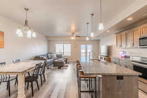 Kitchen featuring sink, decorative light fixtures, light stone counters, and appliances with stainless steel finishes