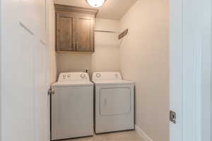 Laundry room featuring cabinets, washing machine and clothes dryer, and light tile patterned floors