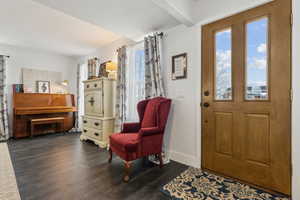 Entryway with dark hardwood / wood-style floors and beam ceiling