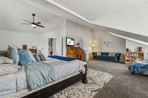 Bedroom with a walk in closet, carpet floors, ceiling fan, and lofted ceiling