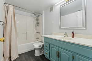 Full bathroom featuring vanity, toilet, wood-type flooring, and shower / tub combo