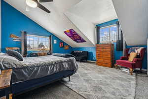 Bedroom with carpet, multiple windows, ceiling fan, and lofted ceiling