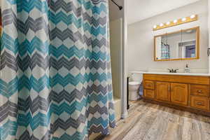 Bathroom featuring toilet, hardwood / wood-style floors, vanity, and a shower with shower curtain