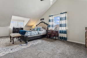 Carpeted bedroom with multiple windows, ceiling fan, and lofted ceiling