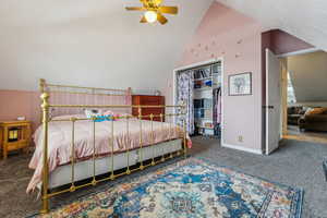 Carpeted bedroom featuring vaulted ceiling, a closet, and ceiling fan