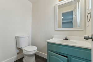 Bathroom with hardwood / wood-style flooring, vanity, and toilet