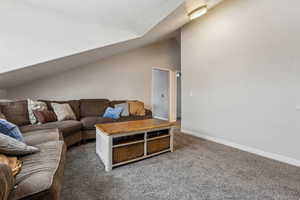 Living room featuring lofted ceiling and dark colored carpet