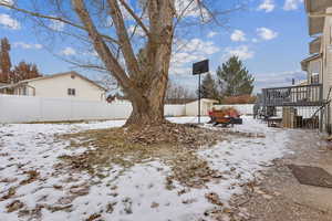 Yard layered in snow featuring a storage unit and a deck