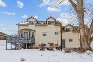 Snow covered rear of property featuring central AC and a deck