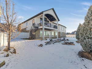 Snow covered rear of property with a balcony