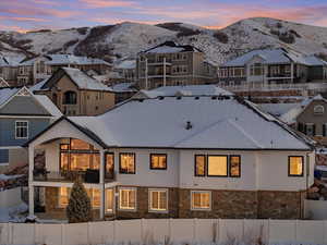 Snow covered back of property featuring a mountain view and a balcony