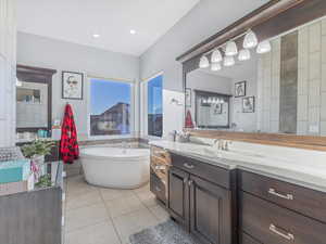 Bathroom featuring tile patterned floors, vanity, and a bath