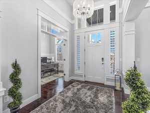 Foyer entrance featuring a notable chandelier, dark hardwood / wood-style floors, and a high ceiling