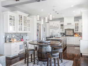 Kitchen featuring backsplash, hanging light fixtures, appliances with stainless steel finishes, a kitchen island, and white cabinetry