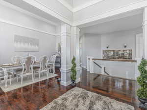 Dining area featuring ornate columns, a towering ceiling, and dark wood-type flooring