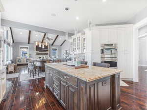 Kitchen featuring ceiling fan, dark brown cabinetry, tasteful backsplash, decorative light fixtures, and stainless steel double oven