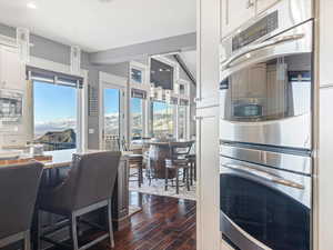 Kitchen featuring appliances with stainless steel finishes, a mountain view, dark hardwood / wood-style floors, white cabinetry, and hanging light fixtures