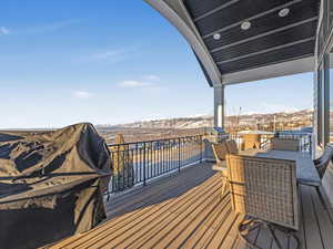 Snow covered deck with a mountain view and a grill