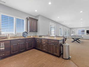 Kitchen featuring dark brown cabinets, kitchen peninsula, and sink