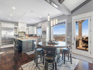 Dining space featuring lofted ceiling with beams, dark hardwood / wood-style flooring, and sink