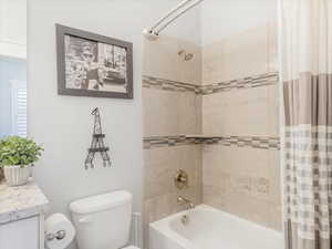 Full bathroom featuring vanity, shower / bath combo, and toilet