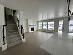 Unfurnished living room featuring a fireplace, a textured ceiling, and hardwood / wood-style floors