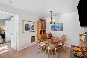 Carpeted dining room with a chandelier and heating unit