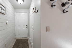 Doorway with wooden walls and light tile patterned floors