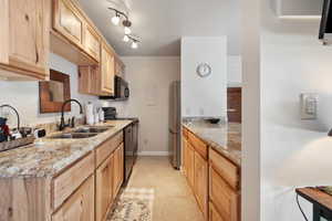 Kitchen featuring light stone counters, sink, light tile patterned floors, rail lighting, and light brown cabinets