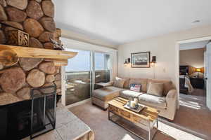 Living room with light colored carpet and a stone fireplace