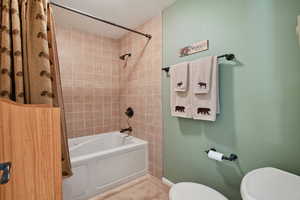 Bathroom featuring tiled shower / bath, tile patterned floors, and toilet