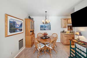 Carpeted dining room featuring a notable chandelier, heating unit, and sink