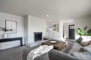 Carpeted living room with a brick fireplace and built in features