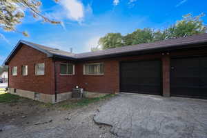 View of side of home with central air condition unit and a garage