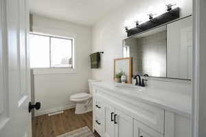 Bathroom with toilet, wood-type flooring, and vanity