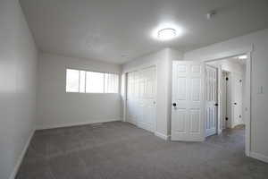 Unfurnished bedroom featuring a closet and dark carpet