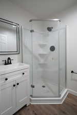 Bathroom with an enclosed shower, vanity, and hardwood / wood-style floors