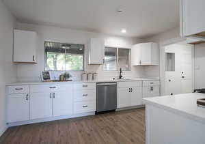 Kitchen featuring sink, dark hardwood / wood-style flooring, white cabinetry, and stainless steel dishwasher