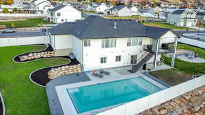 Back of property with central air condition unit, a patio, a yard, and a fenced in pool