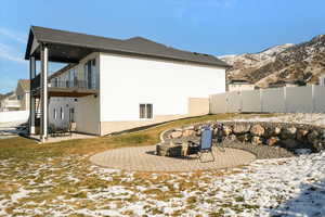 View of snow covered exterior with an outdoor fire pit, a mountain view, and a patio