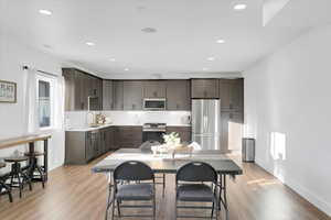 Kitchen featuring sink, stainless steel appliances, light wood-type flooring, and dark brown cabinetry